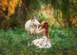 Rudowłosa kobieta obok białego jelenia