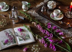 Serwis kawowy i kwiaty obok książki na stole
