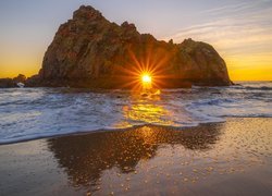 Słońce w łuku Keyhole Arch na plaży Pfeiffer Beach w Kalifornii