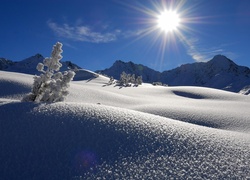 Śnieżne zaspy w blasku wschodzącego słońca na tle gór