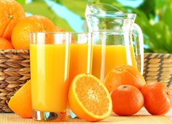 Sok pomarańczowy w dzbanku i szklankach obok pomarańczy i mandarynek