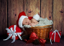 Śpiące niemowlę w koszyku ze świątecznymi prezentami