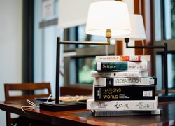 Stos książek pod lampą na biurku