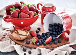 Truskawki i jagody w czerwonych naczyniach