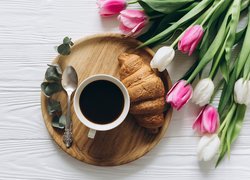 Tulipany obok tacy z kawą i rogalikiem