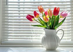 Tulipany w dzbanku przy oknie z żaluzjami