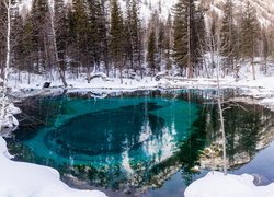 Turkusowe jezioro na tle zimowego lasu