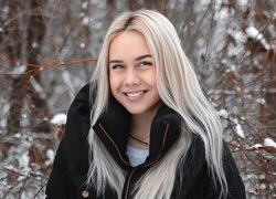 Uśmiechnięta blondynka w zimowym lesie