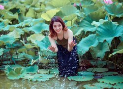 Uśmiechnięta dziewczyna pośród liści lotosu w wodzie