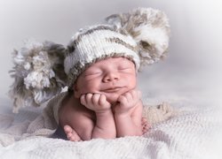 Uśmiechnięte śpiące niemowlę w czapeczce