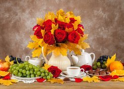 Wazon z różami i liśćmi klonu obok kawy i owoców