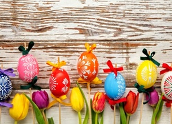 Wielkanocna dekoracja z kolorowych pisanek na patyczkach i tulipanów
