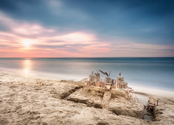 Zamek z piasku na morskiej plaży o wschodzie słońca