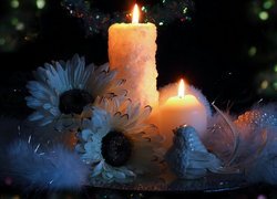 Zapalone świece obok figurki ptaka i kwiatów