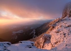 Zimowy krajobraz górski z zamglonym lasem w dolinie o świcie
