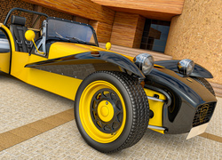Żółto-czarny sportowy samochód Lotus Super Seven na podjeździe